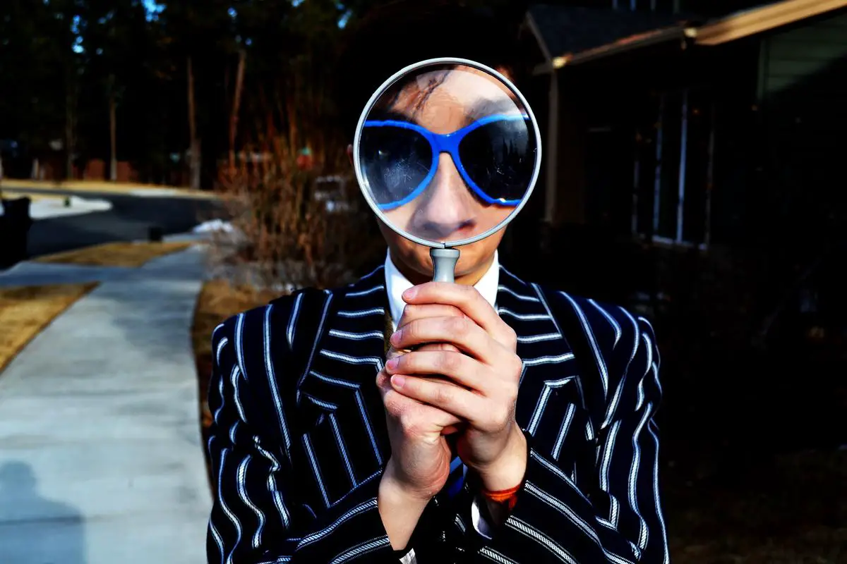 A magnifying glass observing two business people having a race, representing competition analysis.